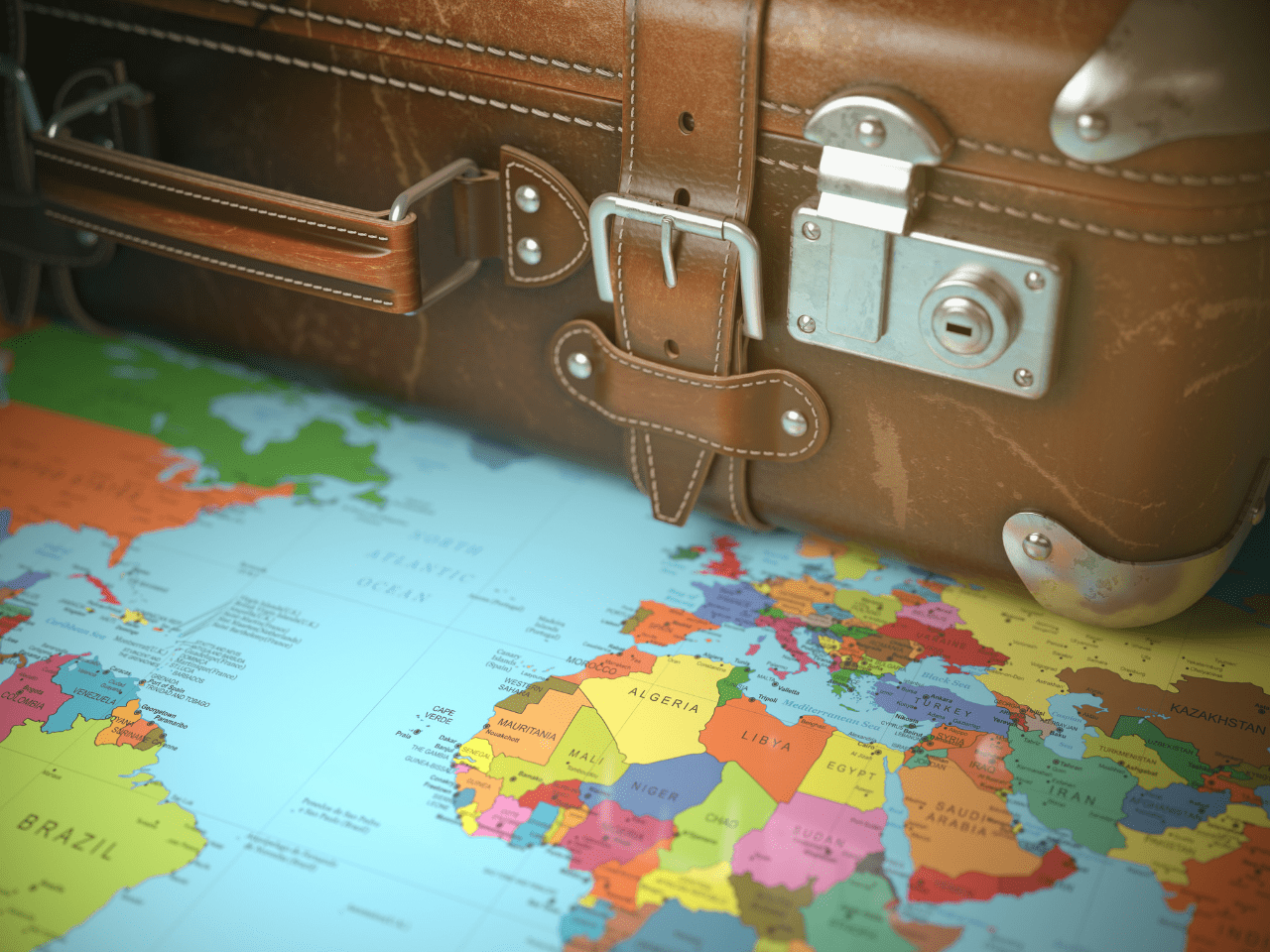 A brown leather suitcase rests on a colorful world map, with regions of Europe, Africa, and South America visible.